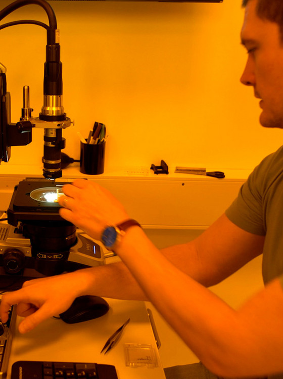 A person sitting in front of a microscope