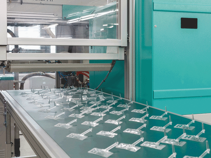 Animated GIF of PMMA replicas on a manufacturing belt and a close-up image of the replica fabricated by high-precision injection molding.
