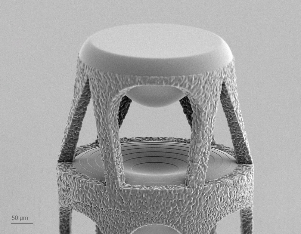 Close-up of the stacked lens system, showing the freeform top lens and the central hybrid lens with its diffractive element