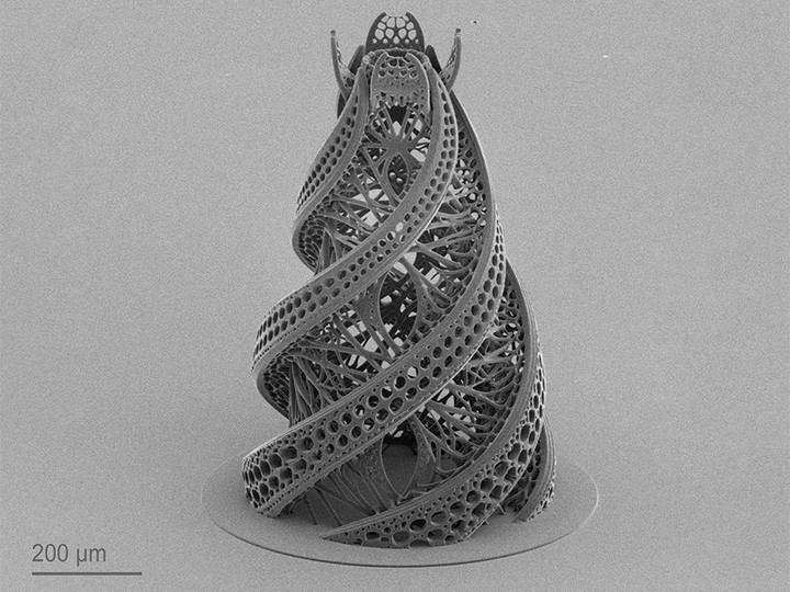 Microscale twisted tower featuring intricate lattice structures and porous surfaces. 